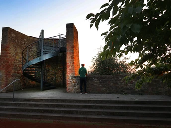 Ein Mensch genießt einen ruhigen Moment auf einer Aussichtsplattform mit steinernem Treppenaufgang.