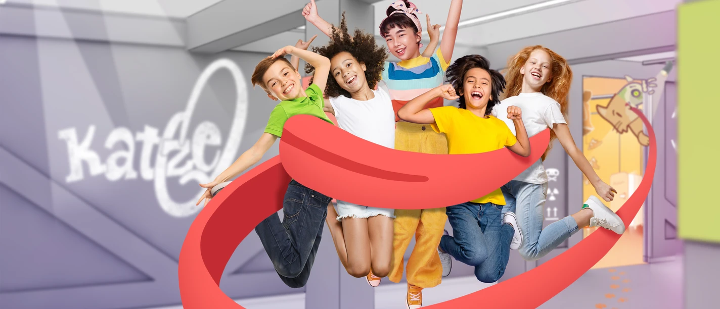 1_EscapeRoom_KatzeQ_AbbildungTamschickMedia+Space GmbH-PhilippStollenmayer-kamibox_highres.png Fünf fröhliche Kinder springen im Escape Room von Katze Q mit roten Bändern im Vordergrund.