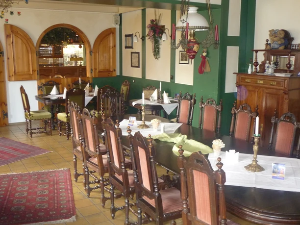 Restaurant Hotel Isselhorster Landhaus Gemütliche Essstube mit langen Holztischen, antiken Stühlen, rustikaler Dekoration und Kerzenleuchtern.