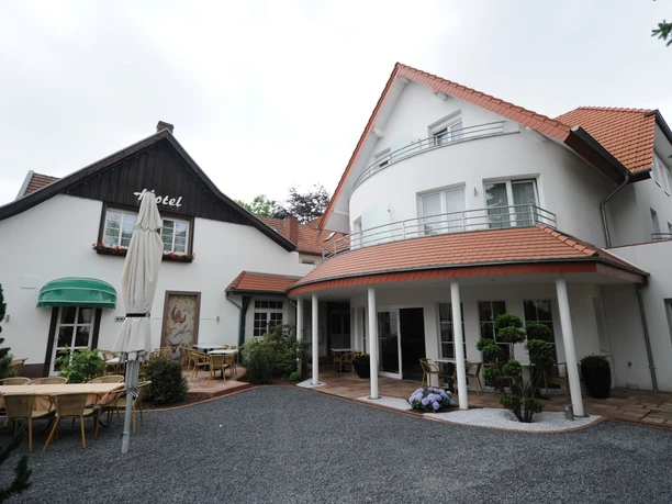 Außenansicht Isselhorster Landhaus Außenansicht eines Landhotels mit Terrassenbereich, mehreren Sitzgruppen und rotem Ziegeldach.