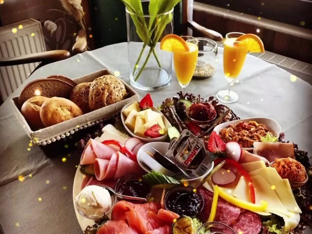 Altes Fährhaus Zu sehen ist ein reichhaltiges Frühstück im Alten Fährhaus, bei dem der Tisch liebevoll gedeckt ist – mit frisch gepressten Orangensäften, einem Körbchen knuspriger Brötchen sowie einer Auswahl an Aufstrichen, Aufschnitt und frischem Obst.