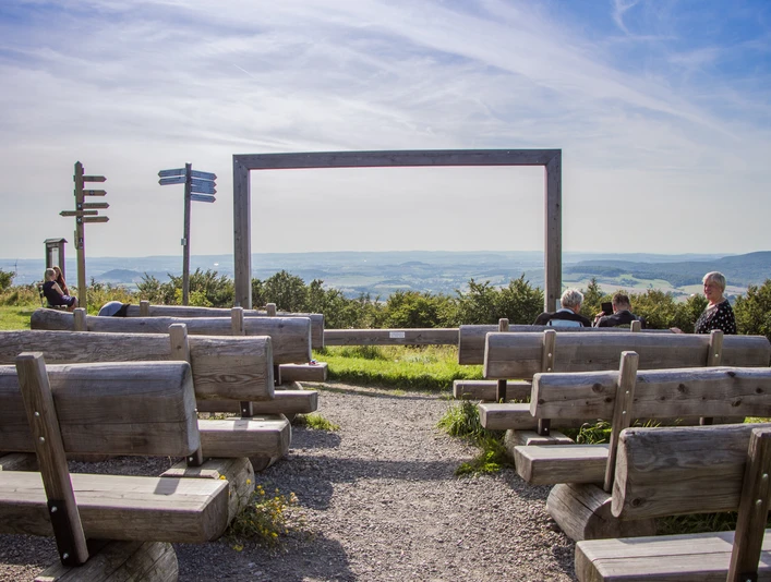 Landschaftskino Köterberg Freiluftkino auf dem Köterberg, Holzbänke mit Aussicht auf weite Hügel und geführte Wanderwege.