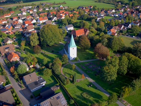 Luftaufnahme von Elbrinxen mit der markanten, historischen Kirche inmitten grüner Landschaft.