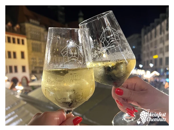 Gläser_Rahmen.jpg Zwei Sektgläser stoßen in nächtlicher Stadtatmosphäre beim Weinfest Chemnitz an.