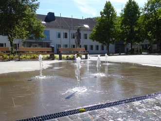 Rathausplatz Morsbach Öffentlicher Platz mit sprudelnden Wasserspielen, Bänken und Bäumen; im Hintergrund Gebäudefront.