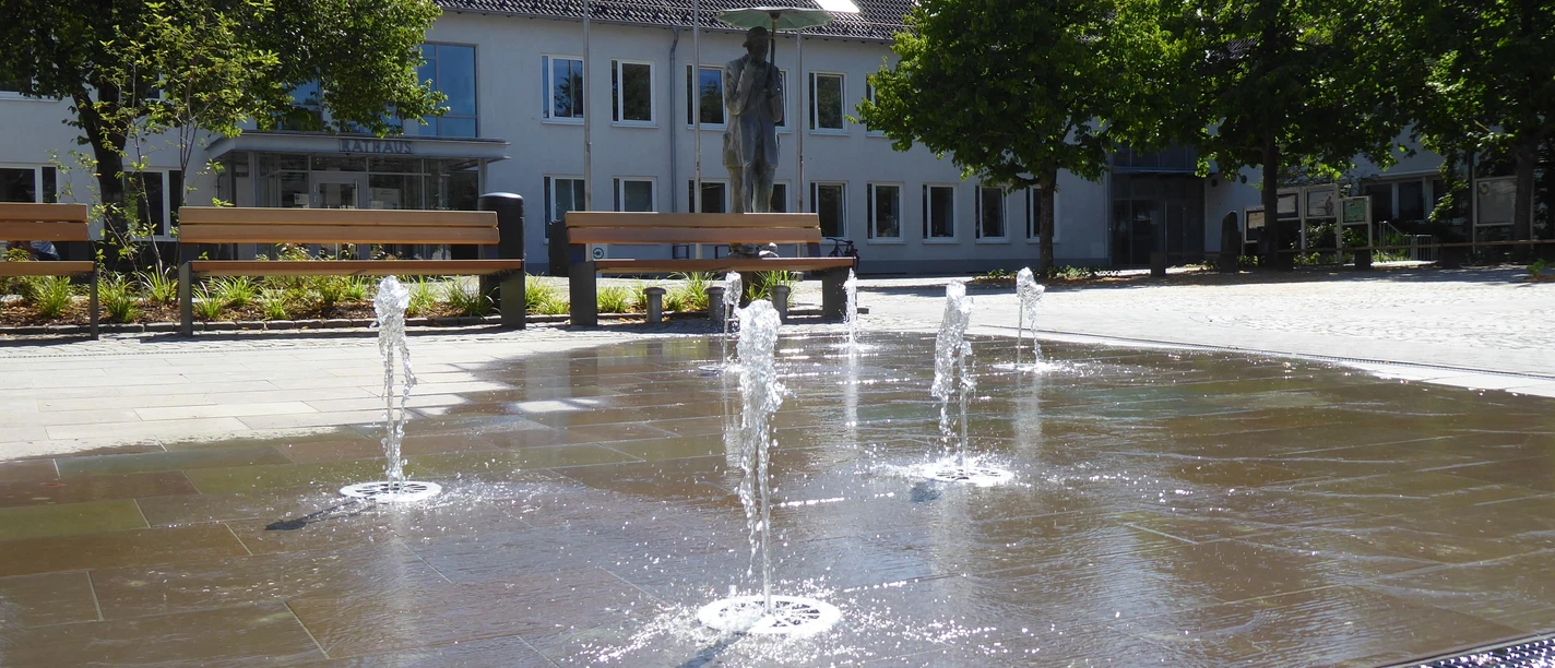 Rathausplatz Morsbach Öffentlicher Platz mit sprudelnden Wasserspielen, Bänken und Bäumen; im Hintergrund Gebäudefront.