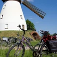Stadt Petershagen_Heimsen_Evelyn Hotze_Mühle_außen_einzelnes Rad im Vordergrund_Sommer_hoch.jpg Historische Windmühle mit langem Flügelwerk in ruhigem Umfeld; Fahrrad im Vordergrund.