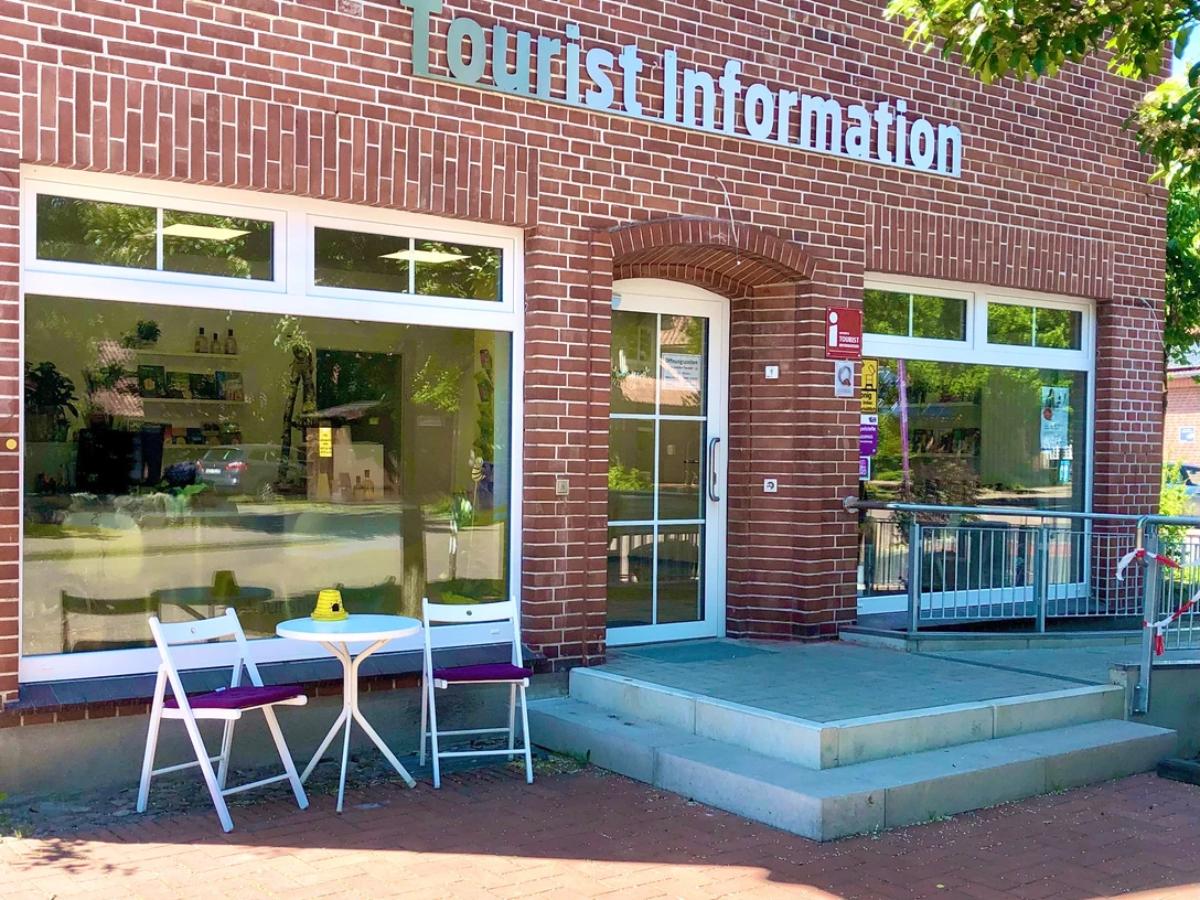 Tourist information Ein rotes Backsteingebäude mit der Aufschrift "Tourist Information". Ein Tisch und zwei Stühle stehen vor dem Eingang.A red brick building with the inscription "Tourist Information". A table and two chairs stand in front of the entrance.En rød murstensbygning med påskriften "Turistinformation". Et bord og to stole står foran indgangen.Een rood bakstenen gebouw met het opschrift "Tourist Information". Een tafel en twee stoelen staan voor de ingang.
