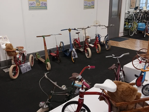 Bismarck Ausstellung Eine Sammlung von bunten Vintage-Kinderfahrzeugen und Rollern in einem Ausstellungsraum.