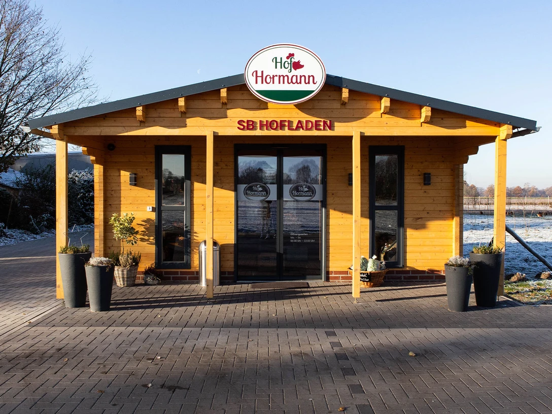 Hofladen Außen.jpg Ein kleiner, rustikaler Selbstbedienungs-Hofladen aus Holz in ländlicher Umgebung mit Winterhintergrund.