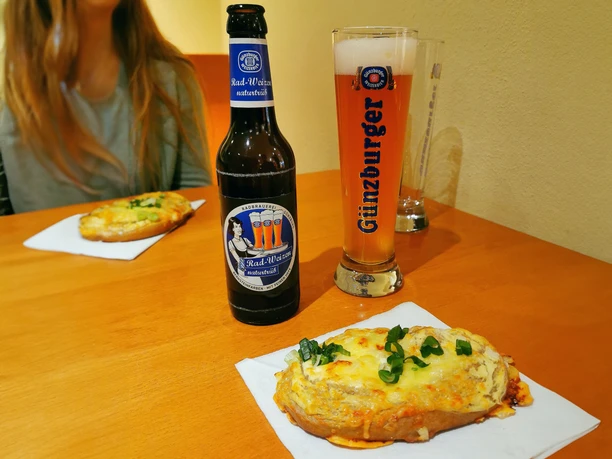 Kulinarische Stadtführung "Günzburg zum Probieren" Eine Flasche Günzburger Radbier und ein Glas stehen auf einem Tisch neben belegten gebackenen Fladen.