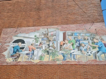 Fassadengemälde zeigt eine detailreiche Büroszene auf einer Backsteinwand in Vlotho mit Arbeiterfiguren.