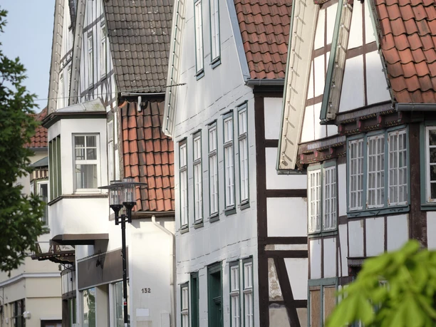 Poelmahn Haus Fachwerkhäuser in Vlotho mit roten Ziegeldächern, Grünpflanzen im Vordergrund, Kopfsteinpflaster.