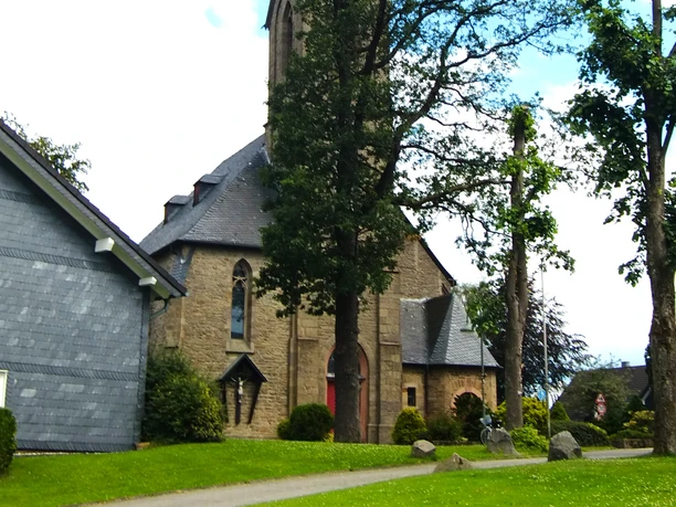 Agathaberg Kirche St. Johann Baptist Kirche in Wipperfürth, ein historisches Gebäude umgeben von grünen Bäumen.
