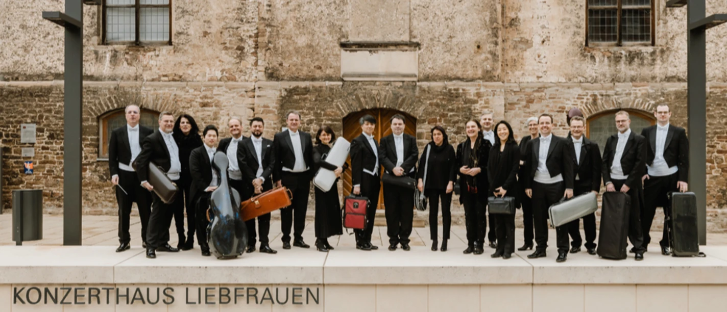 pkow Musikergruppe in Konzertkleidung mit Instrumentenkoffern vor dem Konzerthaus Liebfrauen.