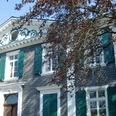 Pulvermuseum Villa Ohl Zweistöckiges historisches Gebäude mit grünen Fensterläden, verziert mit Stuckornamenten und Baum im Vordergrund.