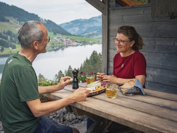 Refreshment at the Hubel Rippa alpine hut Couple of hikers sit in front of the alpine hut and enjoy a cheese and meat platter