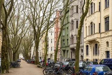 Agnesviertel Die Baumgesäumte Straße mit geparkten Autos und Fahrrädern, flankiert von mehrstöckigen Wohnhäusern aus dem Jugendstil, deutet auf ein urbanes Viertelfest hin.