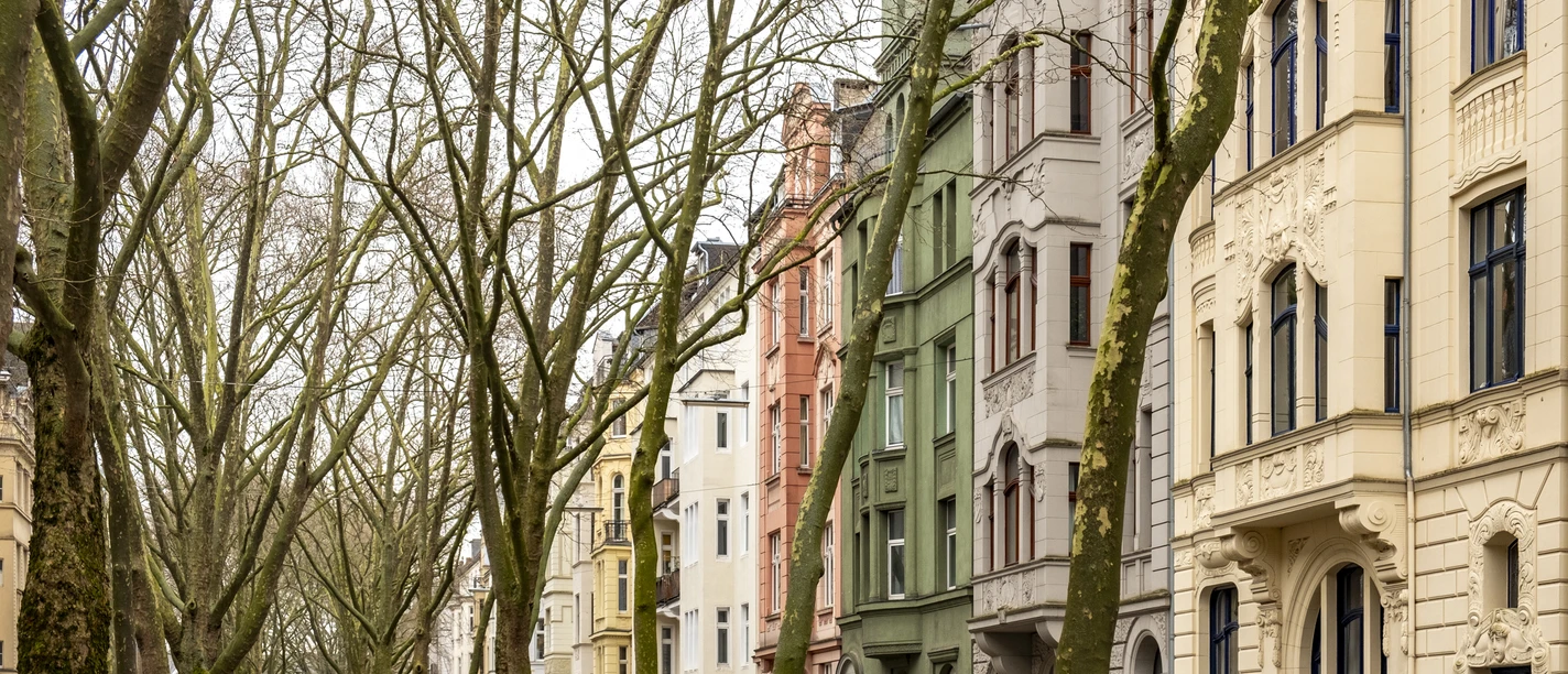 Agnesviertel Die Baumgesäumte Straße mit geparkten Autos und Fahrrädern, flankiert von mehrstöckigen Wohnhäusern aus dem Jugendstil, deutet auf ein urbanes Viertelfest hin.