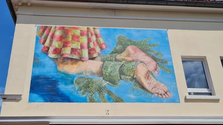 Buntes Wandbild in Vlotho zeigt zwei menschliche Füße in grünen Fischschwanzformen vor blauem Hintergrund.