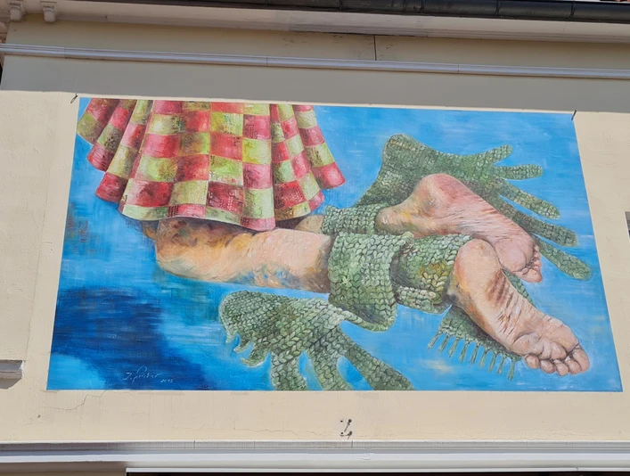 Buntes Wandbild in Vlotho zeigt zwei menschliche Füße in grünen Fischschwanzformen vor blauem Hintergrund.