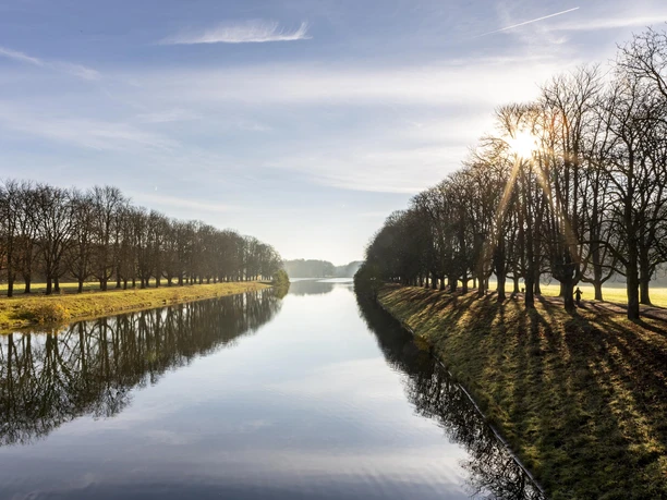 Decksteiner Weiher Der Decksteiner Weiher in Köln, umgeben von sonnenbeschienenen Winterbäumen, reflektiert das klare Himmelblau.