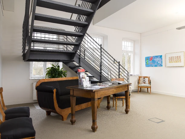 Foyer 1. OG Schloss Foyer with lounge seating and staircase to upper floor