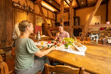 Ferienwohnung Hof Tüschenbonnen <p>Ein Paar genießt Frühstück an einem rustikalen Holztisch mit Gebäck und Blumen in gemütlicher Atmosphäre.</p>