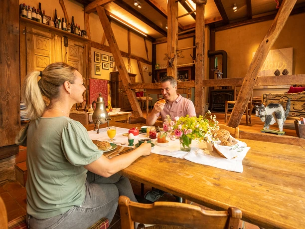 Ferienwohnung Hof Tüschenbonnen <p>Ein Paar genießt Frühstück an einem rustikalen Holztisch mit Gebäck und Blumen in gemütlicher Atmosphäre.</p>
