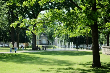 Kaiser-Wilhelm-Platz Detmold Grüner Kaiser-Wilhelm-Platz in Detmold mit Spaziergängern, Bäumen und einem kleinen Brunnen.