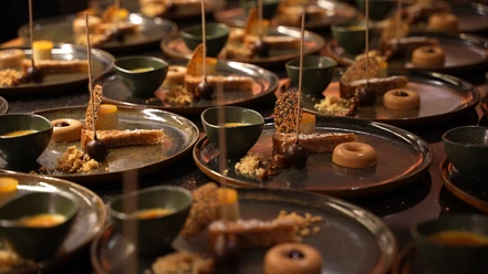 Eine Reihe von kunstvoll angerichteten Desserttellern mit süßen Pralinen und dekorativen Garnierungen.