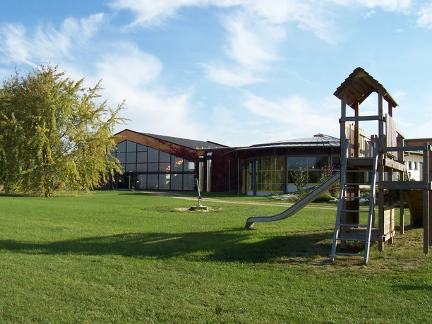 Hallenbad Bad Nenndorf Außenbereich Ein modernes Hallenbad mit Glasfassade, umgeben von einer großzügigen Rasenfläche und einem Spielplatz.