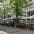 Ristorante Pizzeria Piazza.jpg Auf dem Bild ist die einladende Außenansicht des Restaurants zu sehen, umgeben von üppigen, grünen Bäumen. Gemütliche Sitzgelegenheiten laden dazu ein, die frische Luft zu genießen und im Freien zu speisen.