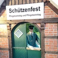 Schützenfest in Gersten Puppe im grünen Schützenanzug steht in Holztor unter Schild mit Aufschrift Schützenfest.