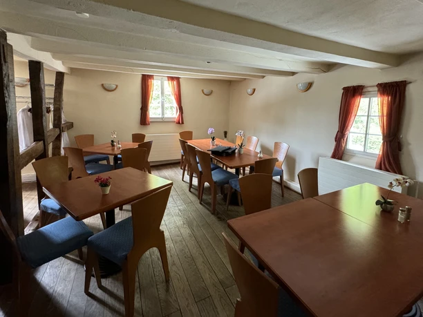 Café Alte Dombach - Innenansicht Das Bild zeigt einen gemütlichen, rustikalen Gastraum mit Holzböden und Holzmöbeln, flankiert von Fenstern.