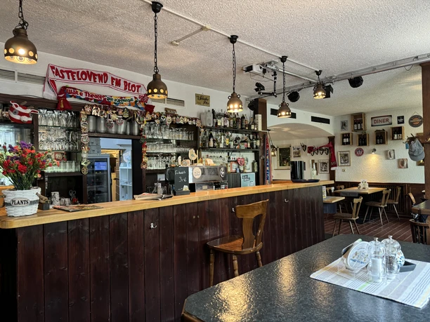 Zur Quelle der Strunde - Ansicht Bar Bar der rustikalen Gaststätte mit Holztresen, dekorativen Gläsern und gemütlichen Sitzgelegenheiten.