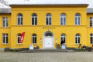 Ratzeburg_Rathaus_TouristInfo5_052024_Petra_Roemer.jpg Rathaus, gelbes Gebäude mit Aufsteller und Fahne für die Tourist-Information