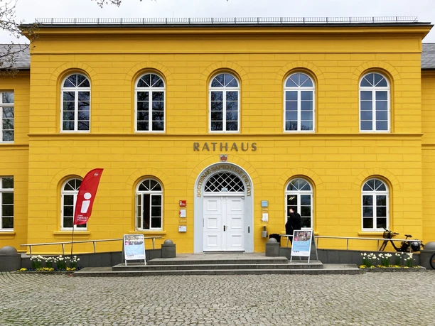 Ratzeburg_Rathaus_TouristInfo5_052024_Petra_Roemer.jpg Rathaus, gelbes Gebäude mit Aufsteller und Fahne für die Tourist-Information