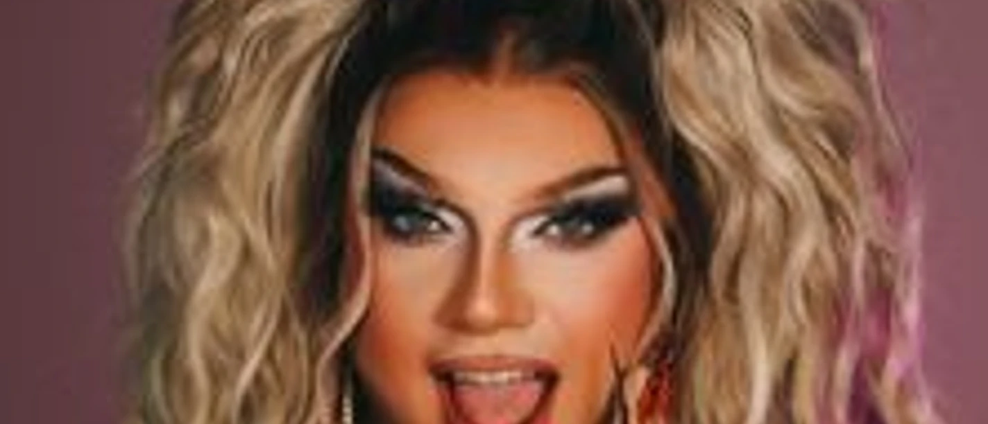 Eine Drag-Queen mit prachtvoll voluminösem Haar, ausdrucksstarkem Make-up und einem lebhaften Gesichtsausdruck.