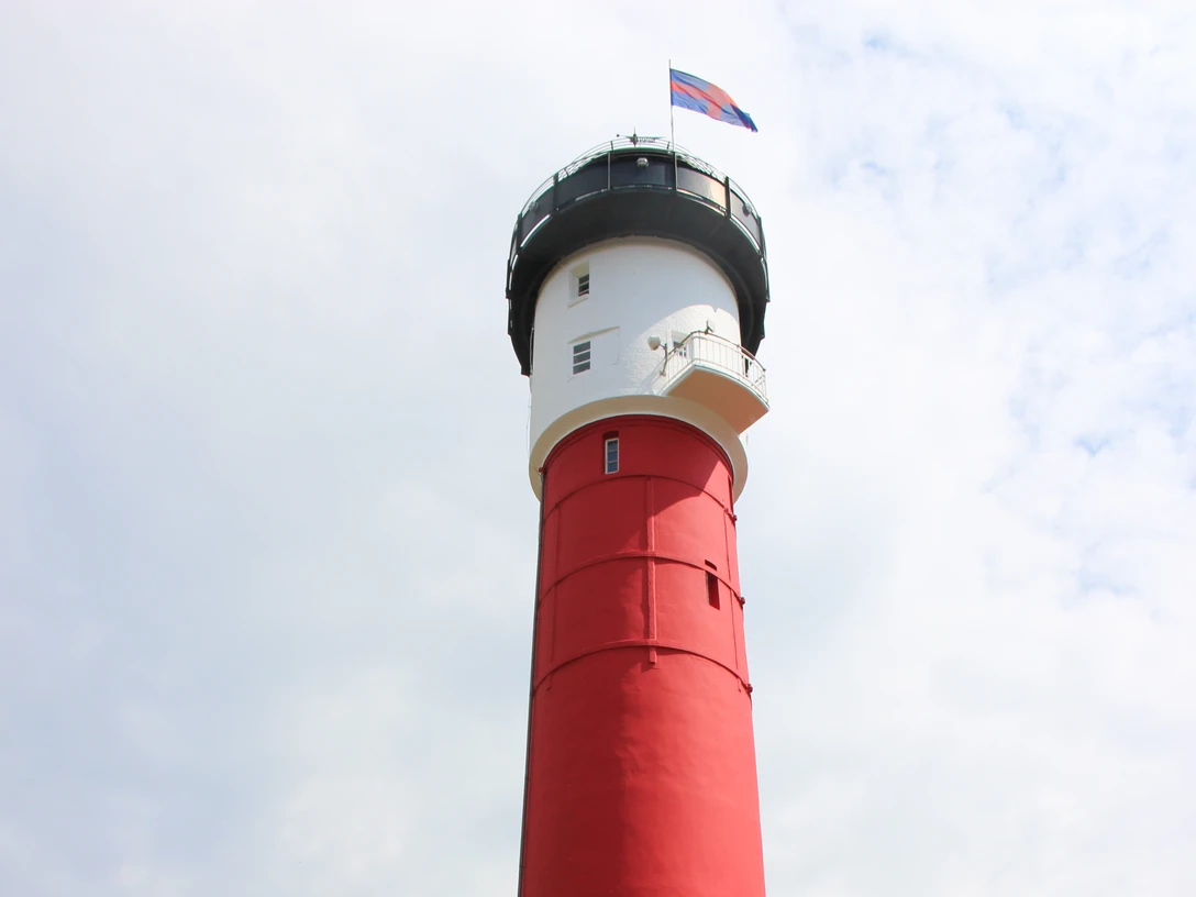 Alter Leuchtturm_c Kurverwaltung Wangerooge.jpg Roter Leuchtturm auf Wangerooge mit vielen Besuchern bei sonnigem Wetter vor dem Turm.