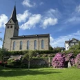evangelische Kirche <p>Historische Kirche in Wiehl mit blühenden Rhododendren und blauem Himmel im Hintergrund.</p>