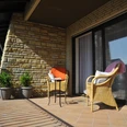 Hotel zur Herzklinik - Balkon.JPG Sonniger Balkon mit Rattansesseln und Tisch, begrenzt von einem geschwungenen Eisenzaun.
