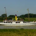 Prinz Heinrich auf der Ems.JPG Das weiße Dampfschiff Prinz Heinrich mit gelbem Schornstein fährt auf der Ems vor grünem Ufer.