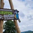 Logo Piratenbucht Hennesee Das Bild zeigt ein hölzernes Schild mit der Aufschrift "Erlebnisspielplatz Piratenbucht am Hennesee", darauf ein bunter Papagei.