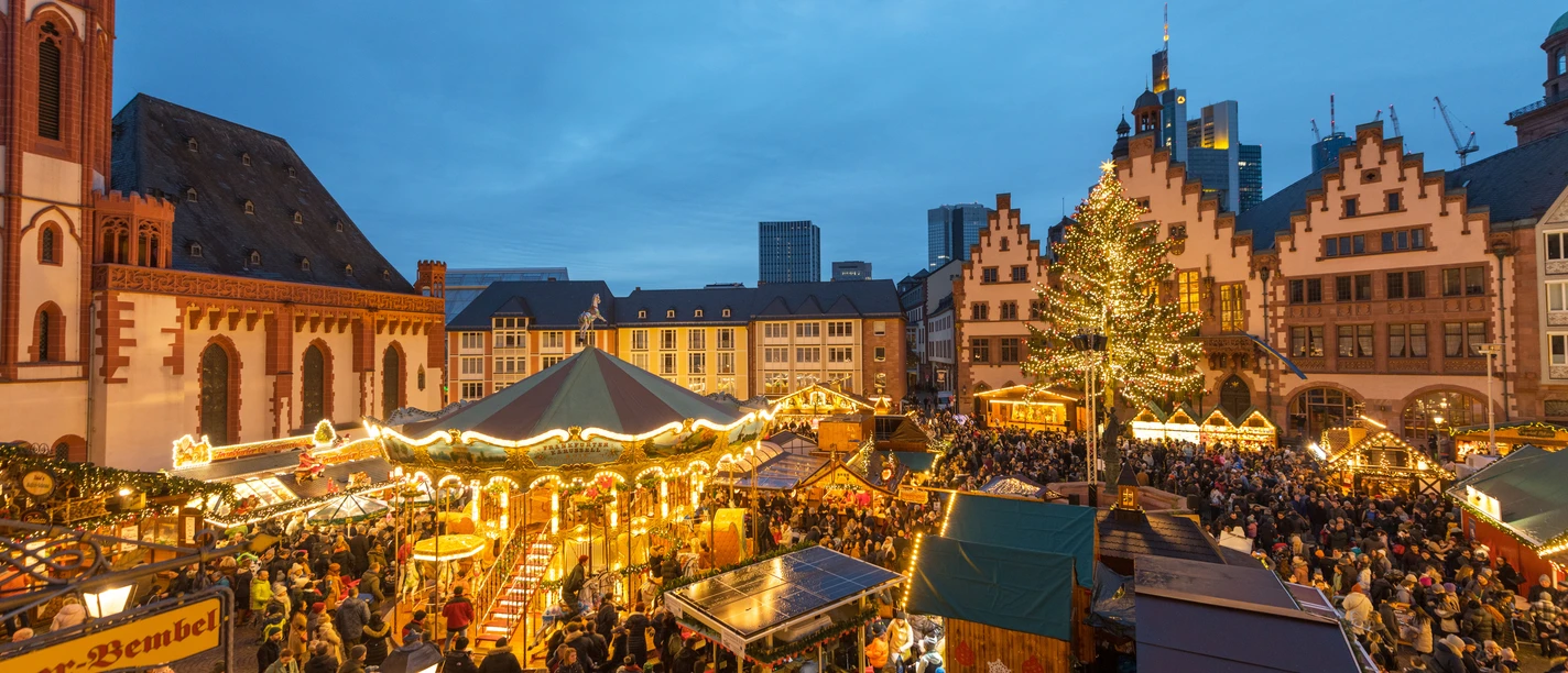 Beleuchteter Weihnachtsmarkt am Römerberg mit Karussell, Tannenbaum und dichtem Gedränge