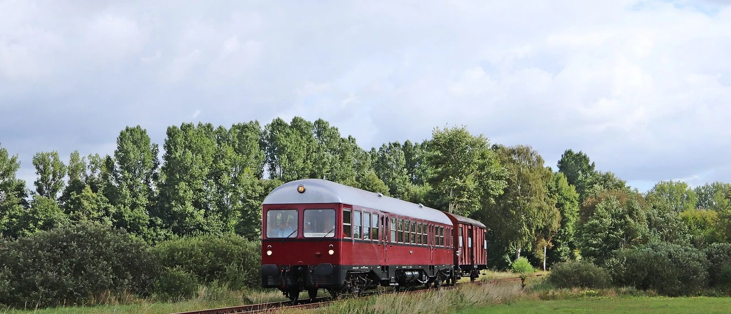 Kleinbahntakt-GDT-0518-im-Bleckeder-Moor-K.-Schulmann.jpeg Roter historischer Triebwagen GDT 0518 fährt durch grüne Wiesenlandschaft im Bleckeder Moor.