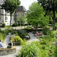 Menschen genießen den gepflegten Schulklostergarten Neuenheerse, umgeben von historischen Gebäuden.