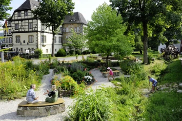 Schulklostergarten Neuenheerse Menschen genießen den gepflegten Schulklostergarten Neuenheerse, umgeben von historischen Gebäuden.
