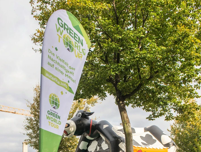 Green World Tour Cologne A father and child sit on a meadow in front of a green cow-shaped bouncy castle at the Green World Tour.
