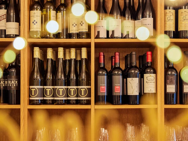 Gasthaus Stromberg, Waltrop Ein Regal voller Weinflaschen, beleuchtet durch sanftes, warmes Licht, das eine einladende Atmosphäre schafft.